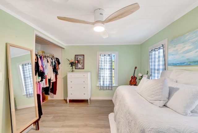 bedroom featuring ceiling fan, baseboards, ornamental molding, light wood-style floors, and a closet