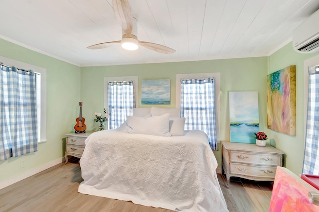 bedroom with ceiling fan, wood finished floors, baseboards, and a wall mounted AC