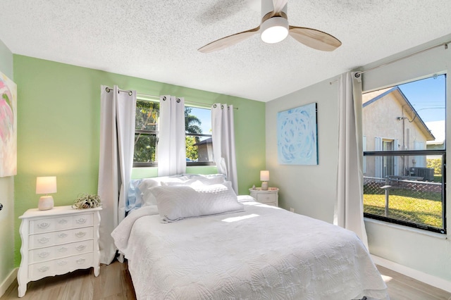 bedroom with baseboards, a textured ceiling, a ceiling fan, and wood finished floors