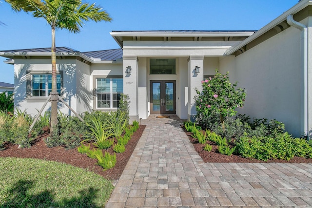 property entrance with a standing seam roof, metal roof, french doors, and stucco siding