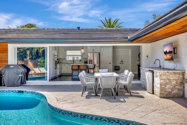 outdoor pool featuring grilling area, outdoor dining area, a patio area, area for grilling, and a sink