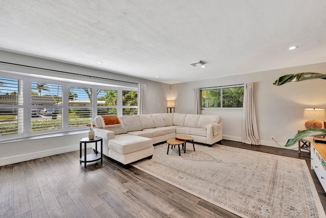 living room with baseboards, a textured ceiling, and dark wood finished floors