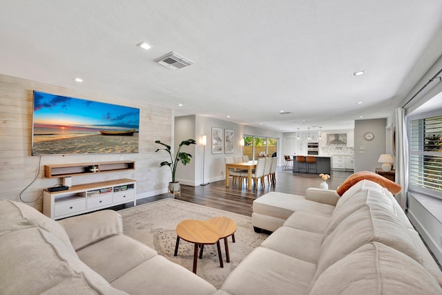 living area with recessed lighting, wooden walls, wood finished floors, and an accent wall