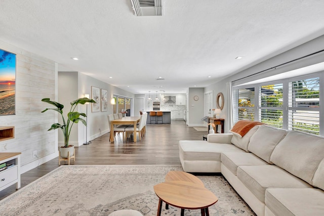 living room with recessed lighting, visible vents, a textured ceiling, and wood finished floors