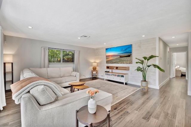 living room featuring recessed lighting, visible vents, wood finished floors, and an accent wall