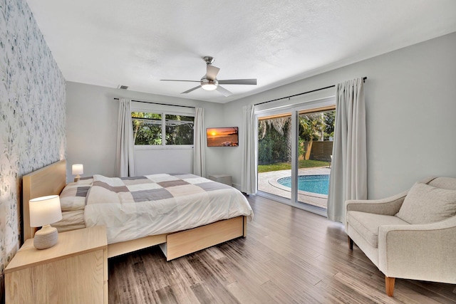 bedroom with visible vents, wallpapered walls, wood finished floors, a ceiling fan, and access to outside