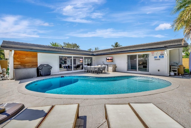 outdoor pool with a grill, outdoor dining area, and a patio