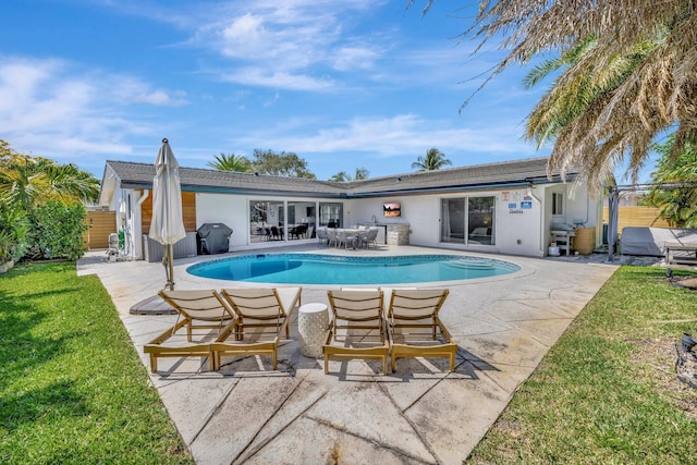 rear view of house with fence, a fenced in pool, a yard, stucco siding, and a patio area