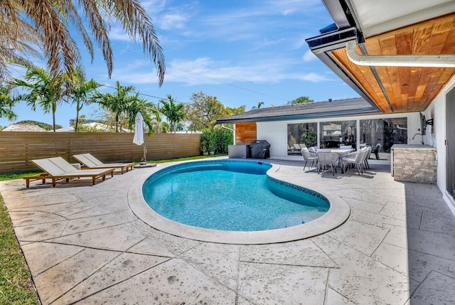 view of swimming pool featuring a patio, fence, a fenced in pool, and grilling area