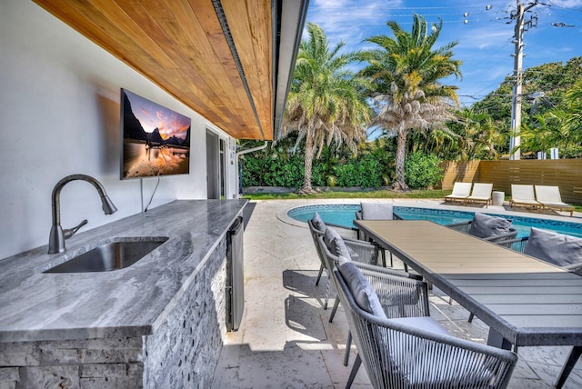 view of swimming pool featuring outdoor dining space, a patio, a fenced in pool, fence, and a sink