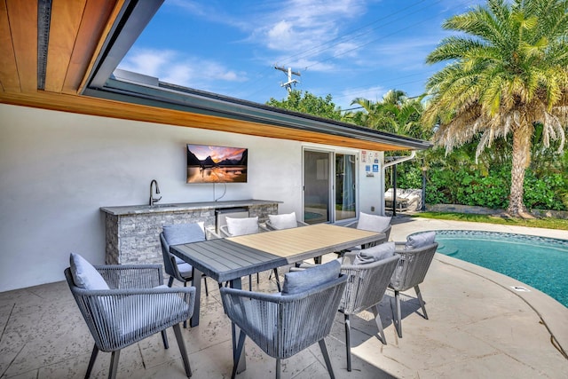 view of patio with an outdoor pool, outdoor dining area, and a sink