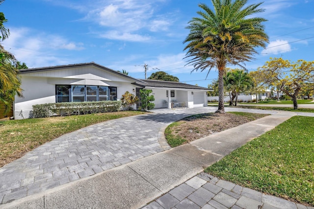 ranch-style house with decorative driveway, a garage, a front lawn, and stucco siding