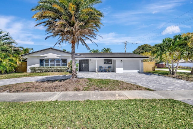 ranch-style house featuring a front yard, decorative driveway, a garage, and stucco siding