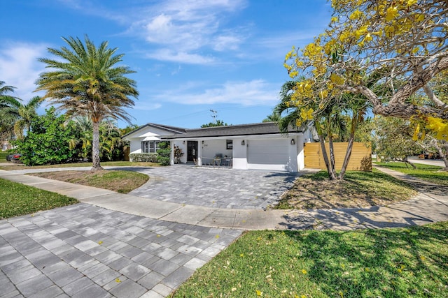 ranch-style home with stucco siding, a front yard, decorative driveway, and a garage