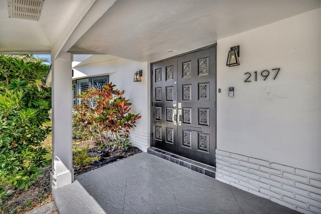 doorway to property featuring visible vents and stucco siding