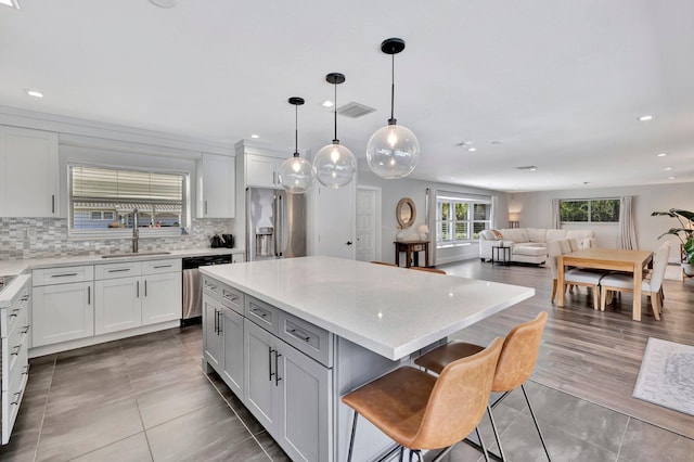 kitchen with a sink, stainless steel appliances, tasteful backsplash, and a center island