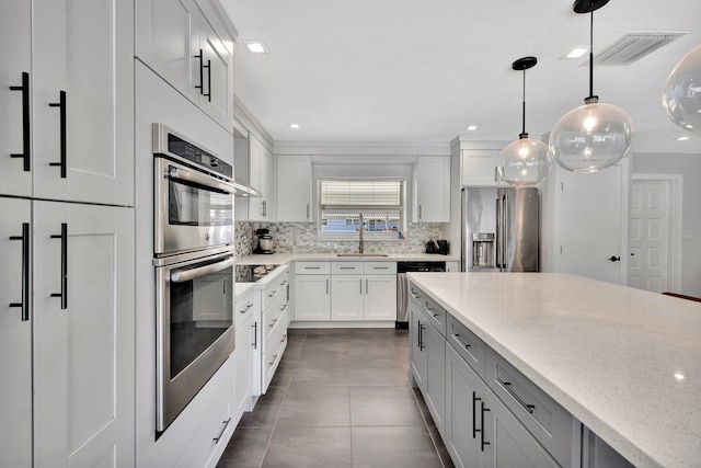 kitchen featuring light stone counters, visible vents, a sink, stainless steel appliances, and backsplash