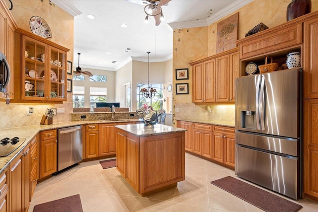 kitchen with a sink, ornamental molding, glass insert cabinets, appliances with stainless steel finishes, and a center island