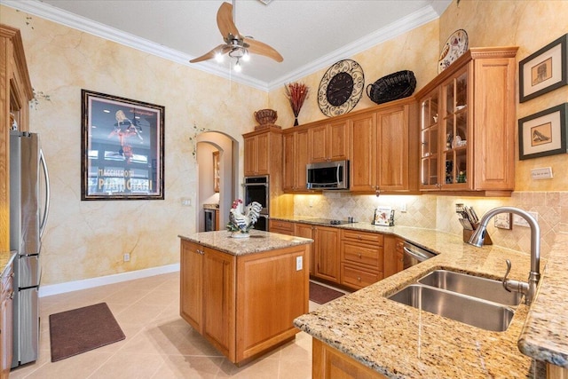 kitchen with ornamental molding, light stone countertops, stainless steel appliances, and a sink