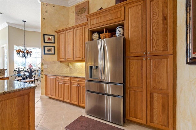 kitchen featuring backsplash, crown molding, light stone countertops, a chandelier, and stainless steel refrigerator with ice dispenser