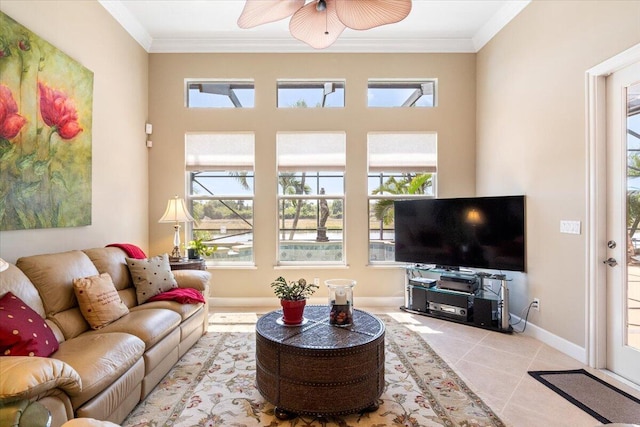 living room featuring baseboards, a ceiling fan, crown molding, and tile patterned flooring