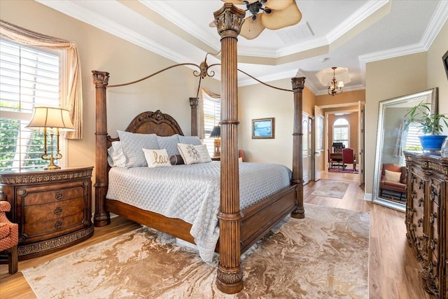 bedroom with a tray ceiling, wood finished floors, visible vents, and ornamental molding