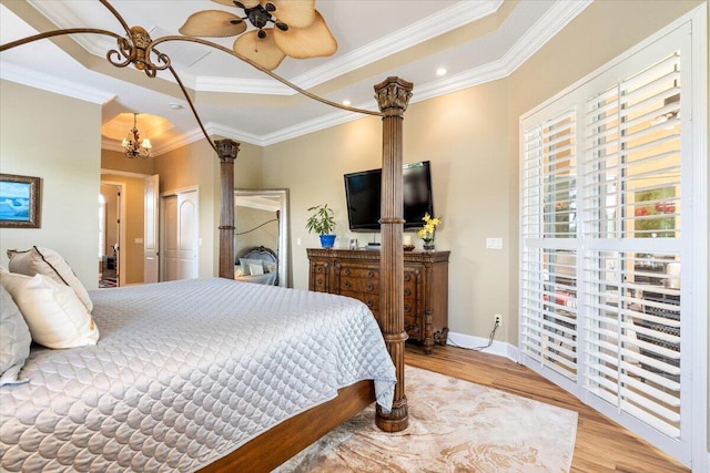 bedroom featuring a tray ceiling, crown molding, wood finished floors, and baseboards