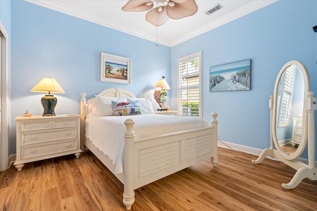 bedroom with wood finished floors, visible vents, baseboards, ceiling fan, and crown molding