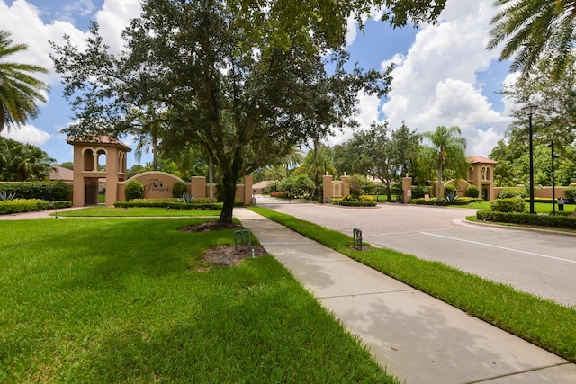 view of road with curbs, sidewalks, street lighting, and a gated entry