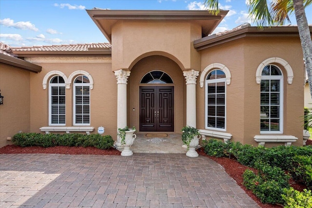 property entrance featuring a tiled roof and stucco siding