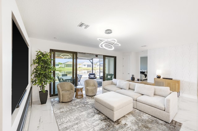 living area with a notable chandelier, visible vents, marble finish floor, and wallpapered walls