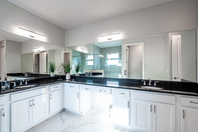 bathroom featuring double vanity, marble finish floor, a stall shower, and a sink