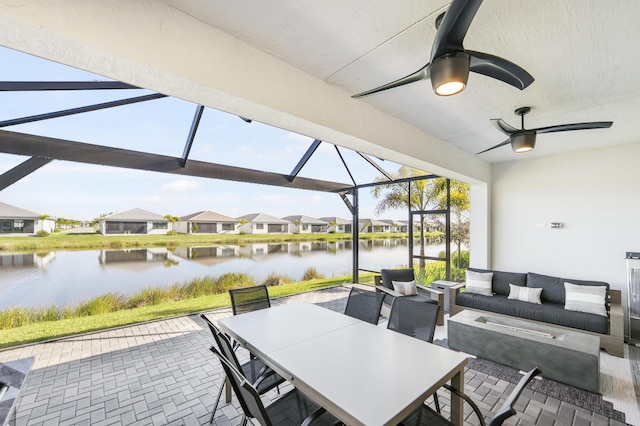 view of patio featuring glass enclosure, outdoor dining space, a ceiling fan, an outdoor living space, and a water view