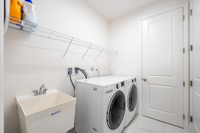 clothes washing area featuring a sink, marble finish floor, laundry area, and washer and clothes dryer