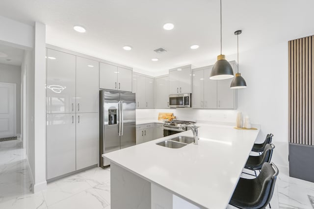 kitchen with a sink, marble finish floor, appliances with stainless steel finishes, and a peninsula