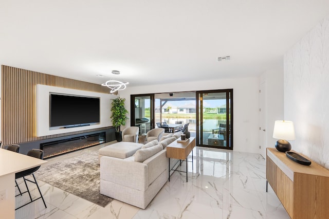 living area featuring an accent wall, visible vents, marble finish floor, and a chandelier