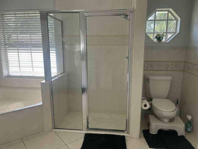 bathroom featuring tile patterned flooring, a shower stall, a garden tub, toilet, and tile walls