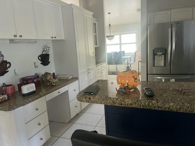 kitchen featuring light tile patterned floors, dark stone countertops, white cabinets, stainless steel fridge, and a textured ceiling