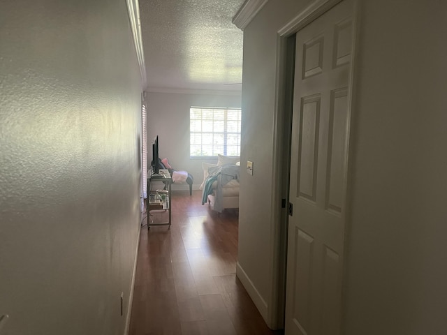 hall featuring baseboards, dark wood-type flooring, crown molding, and a textured ceiling