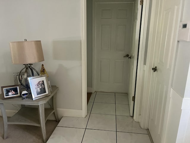 corridor with baseboards and light tile patterned flooring