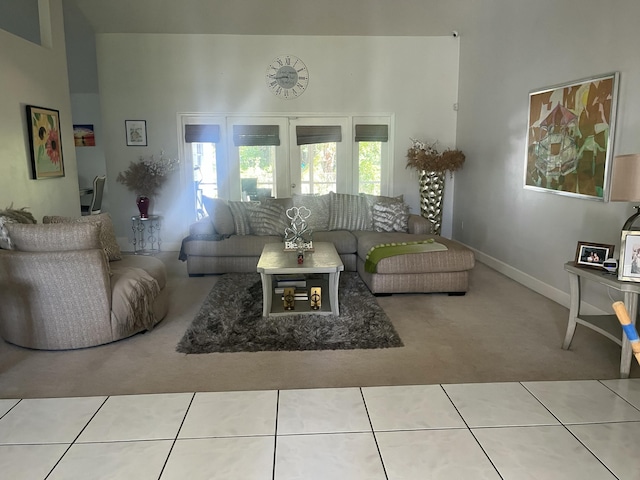 living area featuring tile patterned flooring, french doors, a towering ceiling, and carpet floors