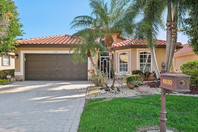 mediterranean / spanish house featuring stucco siding, a tiled roof, an attached garage, and driveway