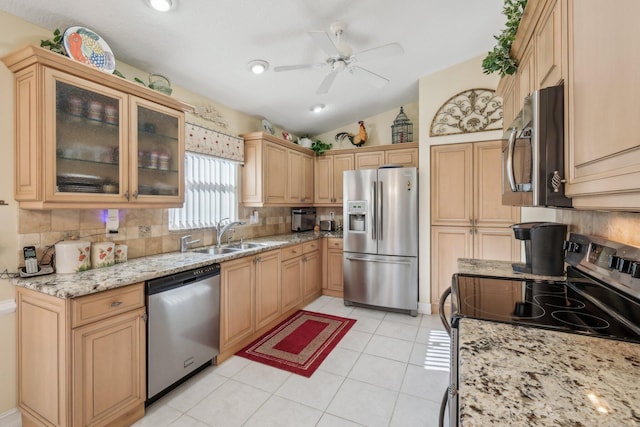 kitchen with backsplash, ceiling fan, light stone countertops, stainless steel appliances, and a sink