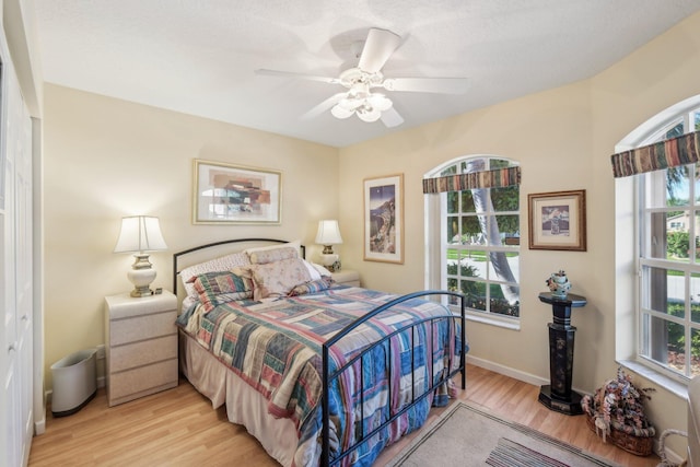 bedroom featuring light wood-style flooring, a ceiling fan, and baseboards
