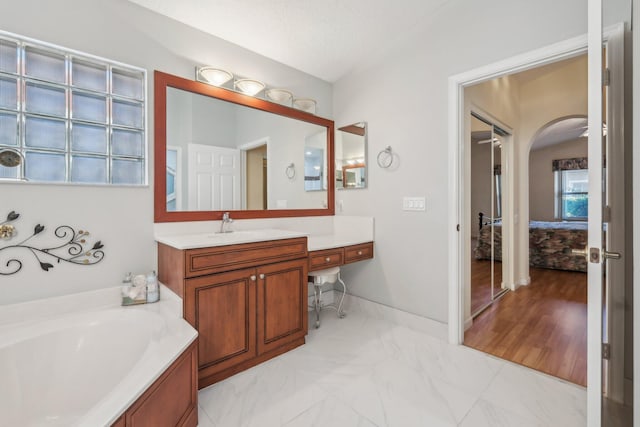 bathroom featuring vanity, a garden tub, baseboards, and marble finish floor