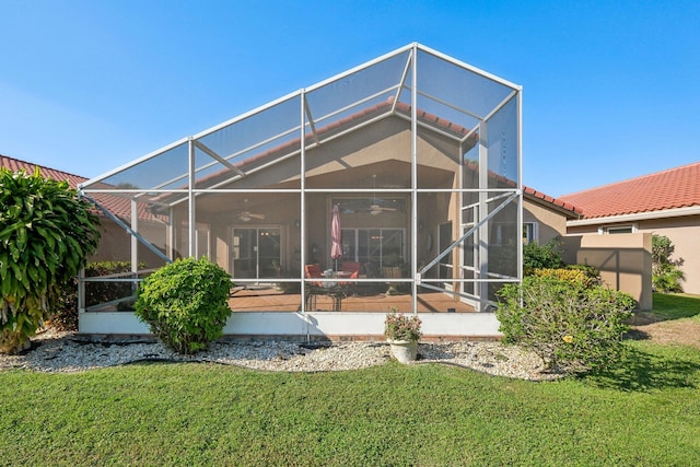 rear view of house featuring stucco siding, a lawn, a tile roof, ceiling fan, and a lanai