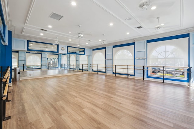 workout area with visible vents, light wood-style flooring, a ceiling fan, and crown molding