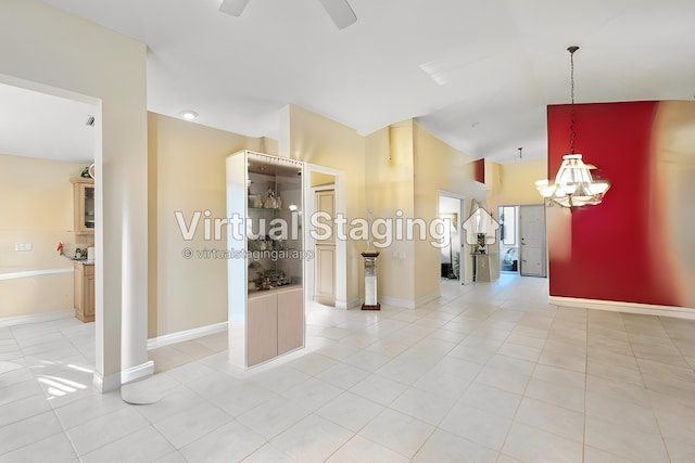 unfurnished room with baseboards, light tile patterned flooring, vaulted ceiling, and ceiling fan with notable chandelier