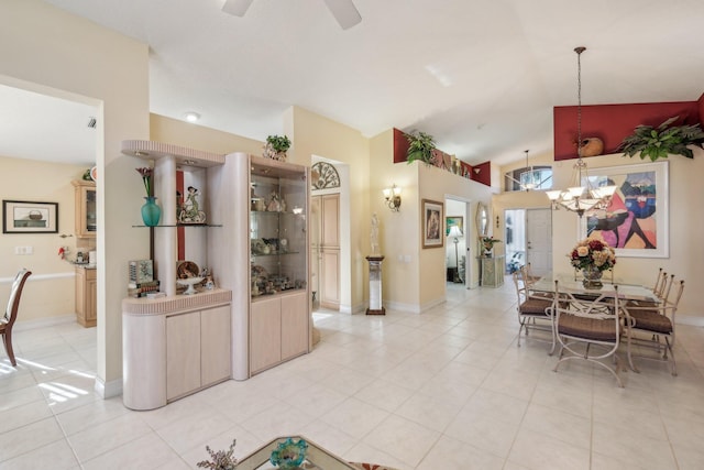 dining area featuring light tile patterned floors, ceiling fan with notable chandelier, baseboards, and lofted ceiling