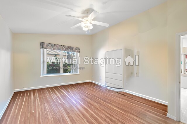 spare room with baseboards, lofted ceiling, ceiling fan, and wood finished floors